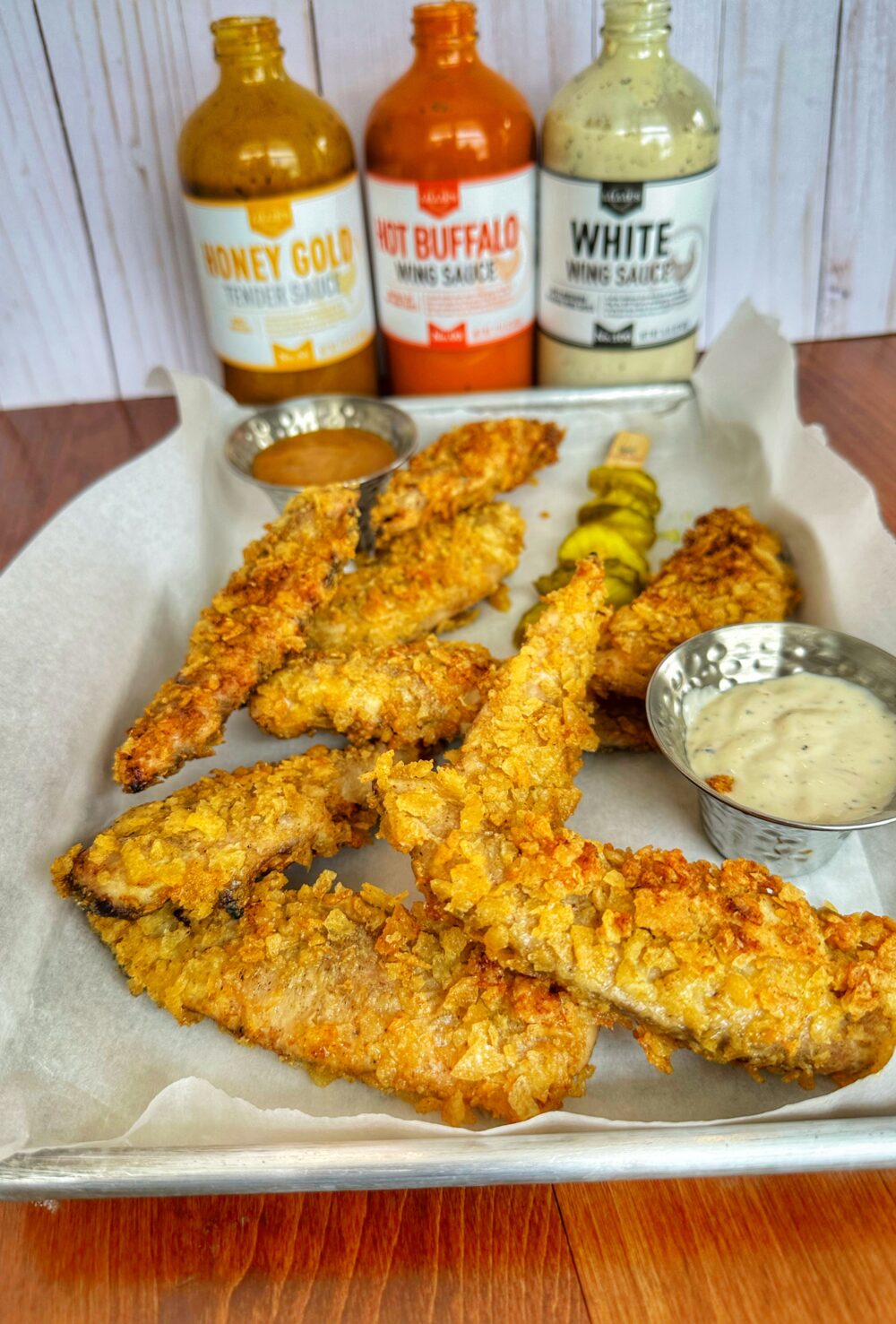 Chicken tenders on a tray with three Lillie's Q Sauces.