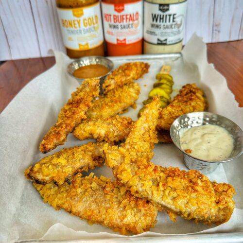 Chicken tenders on a tray with three Lillie's Q Sauces.