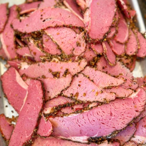 Sliced pastrami pieces on a tray.