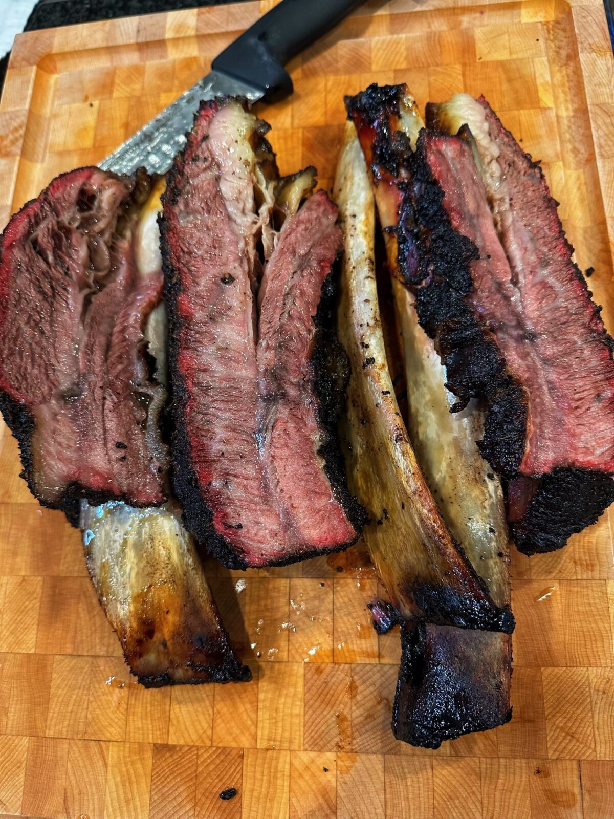 Sliced smoked beef ribs on a cutting board.