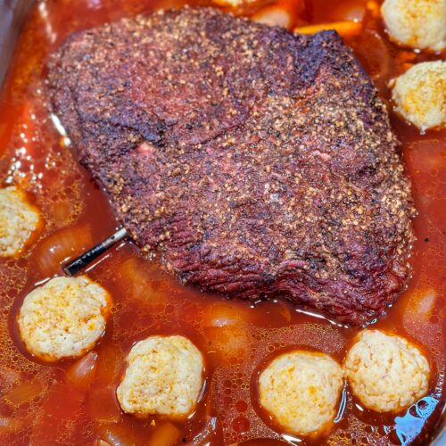 Smoked and braised brisket in a pan with matzoh balls.