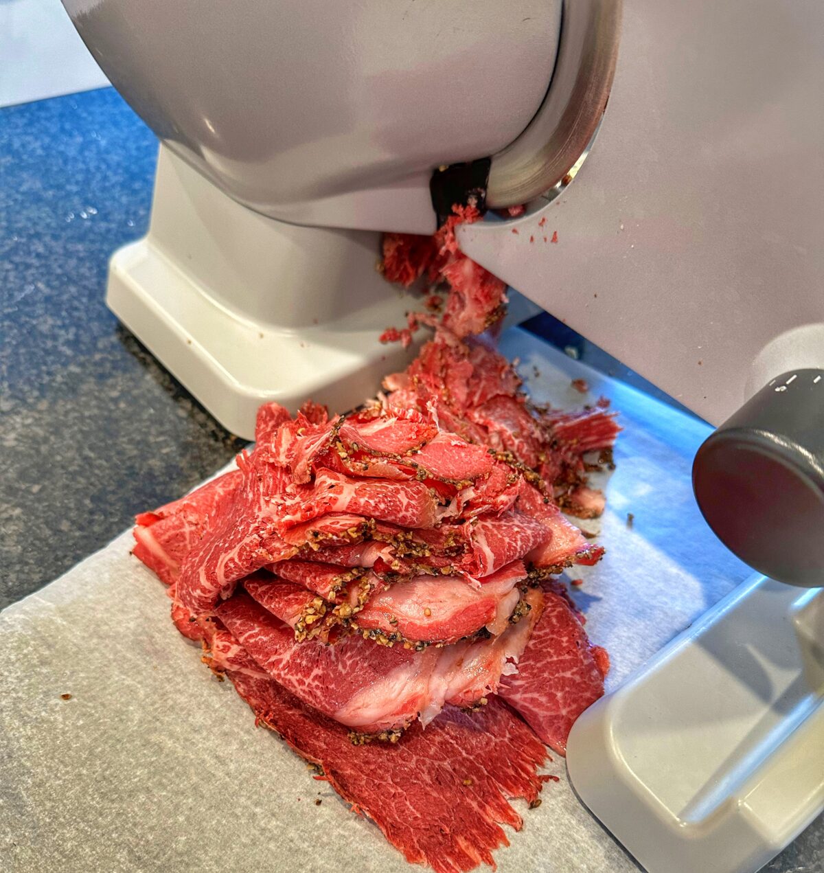 Thinly sliced corned beef on a deli slicer.