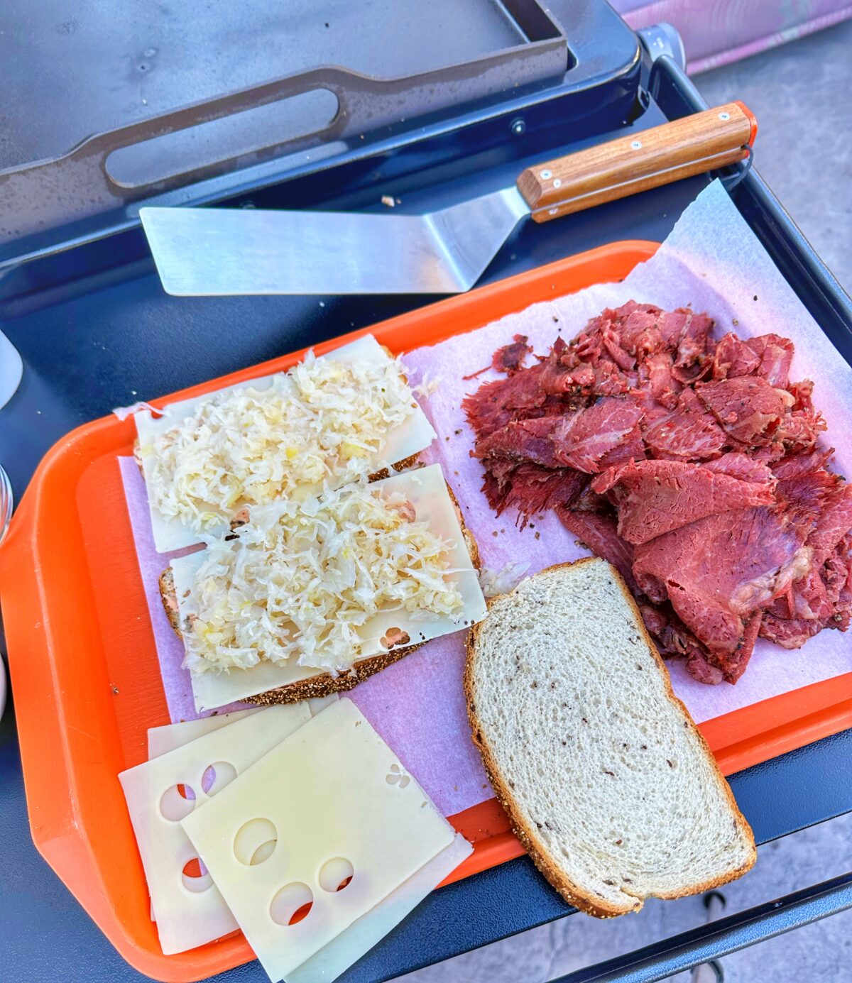Reuben sandwich assembly on an orange tray.