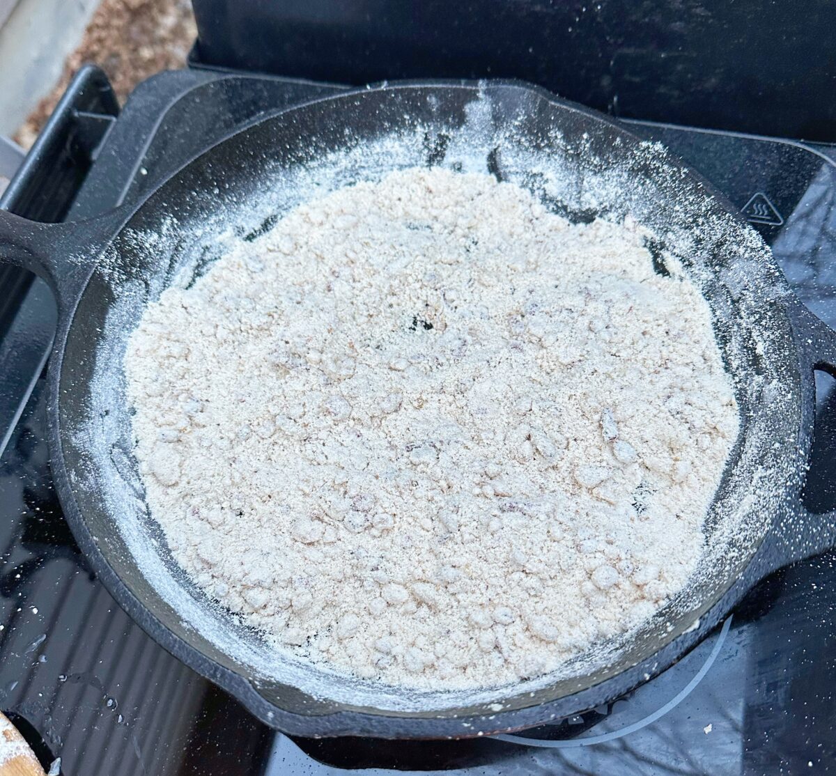 Farofa being cooked in a cast iron skillet.