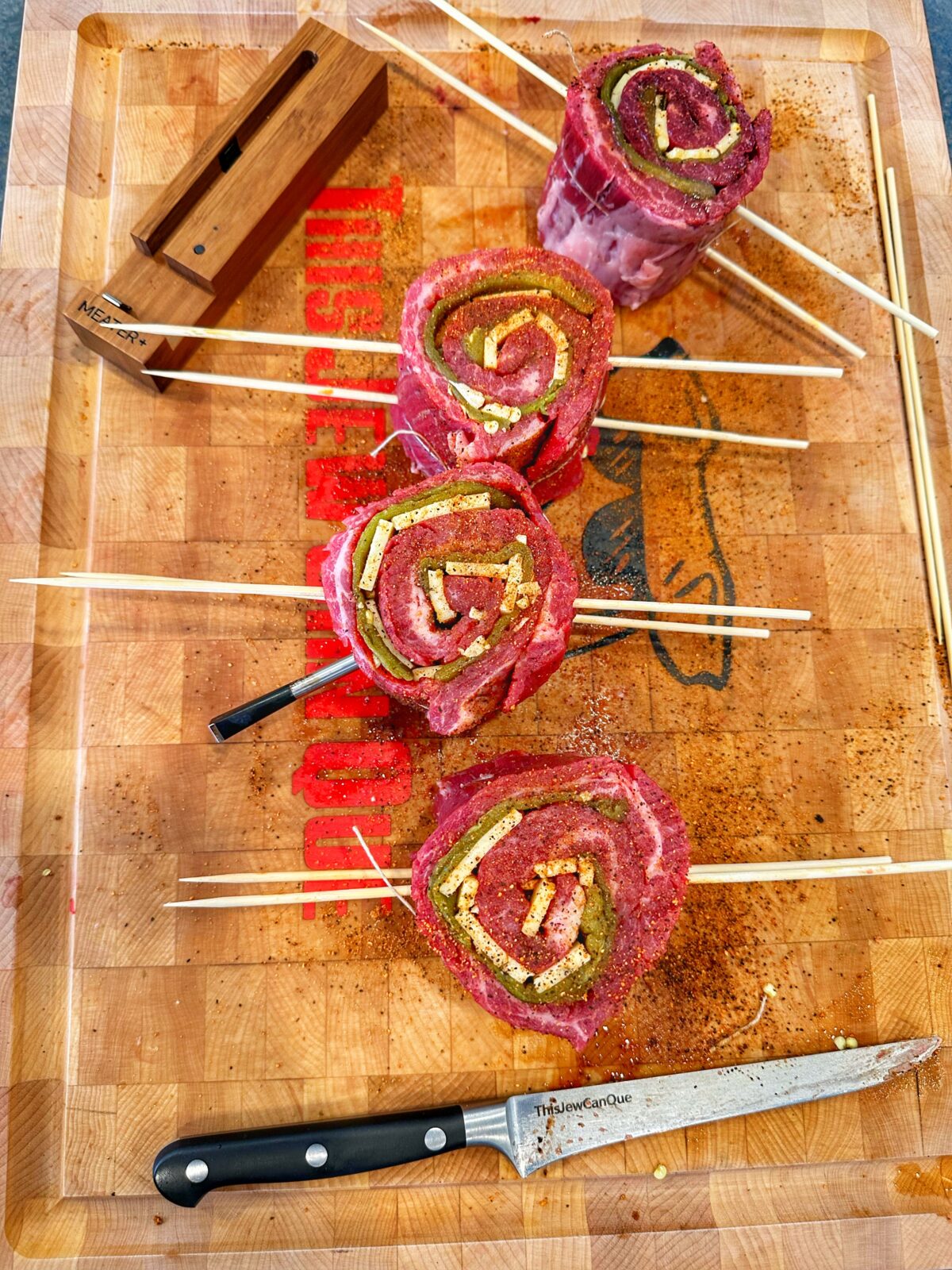 Rolled pinwheels on a cutting board with knife and thermometer.