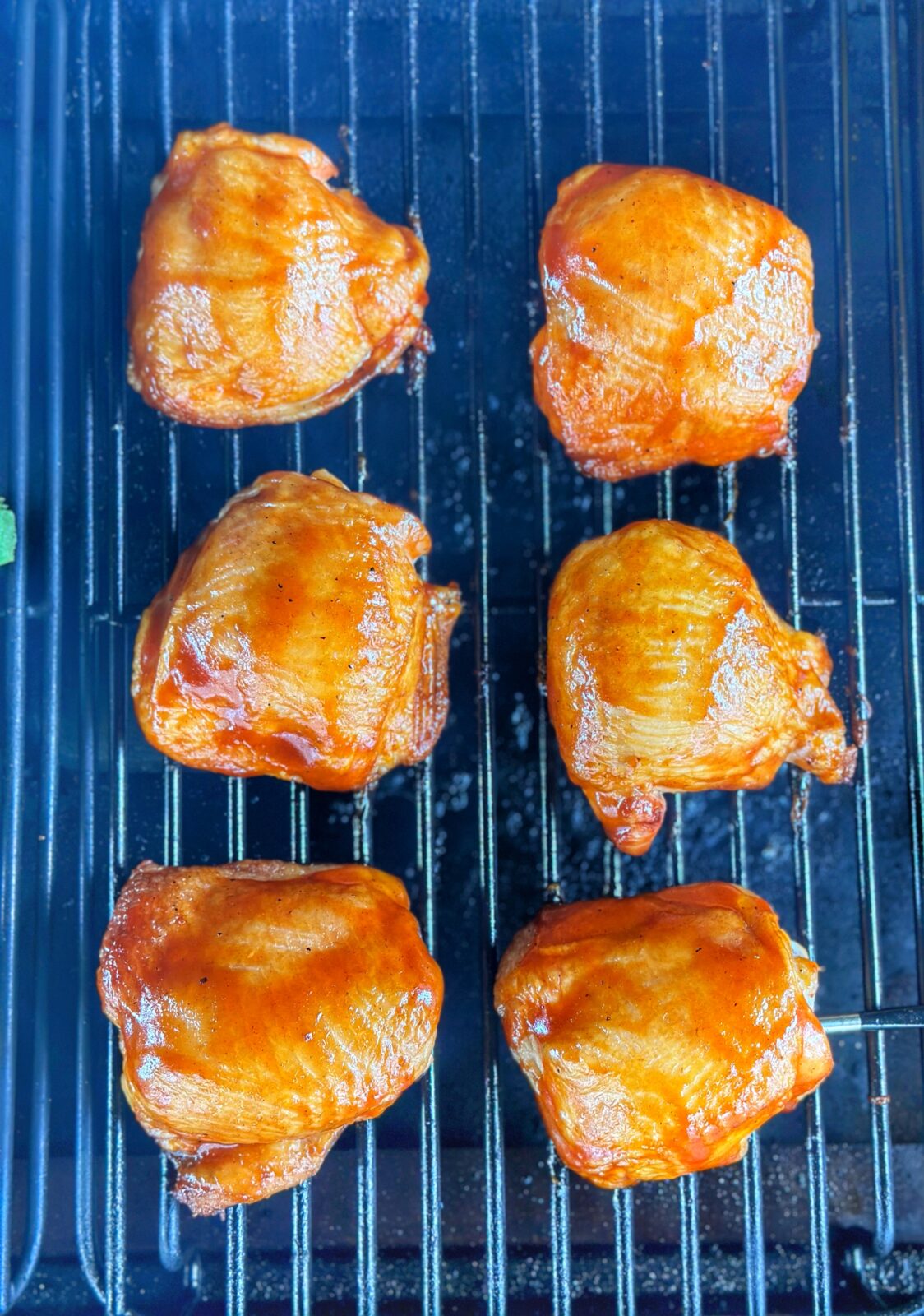 Chicken thighs glazed with BBQ sauce on the grill.