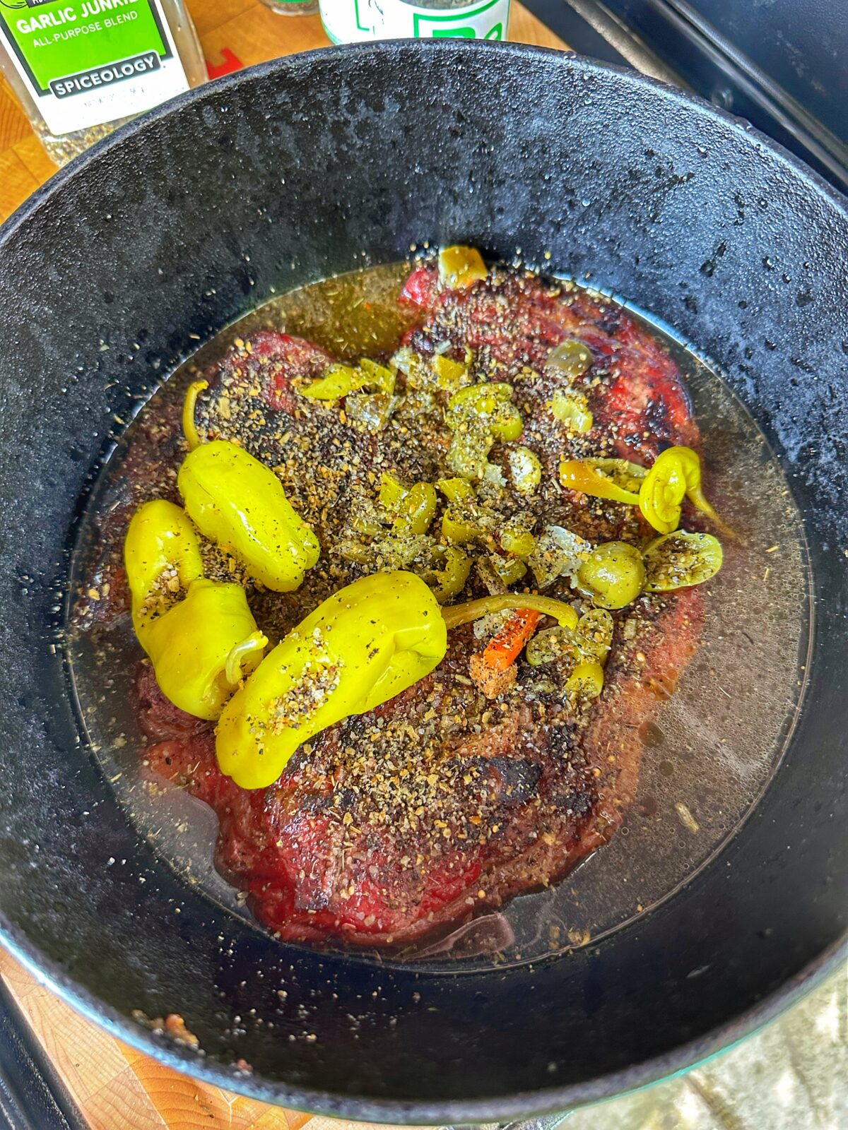 Seared chuck roast in a cast iron dutch oven with braising ingredients.