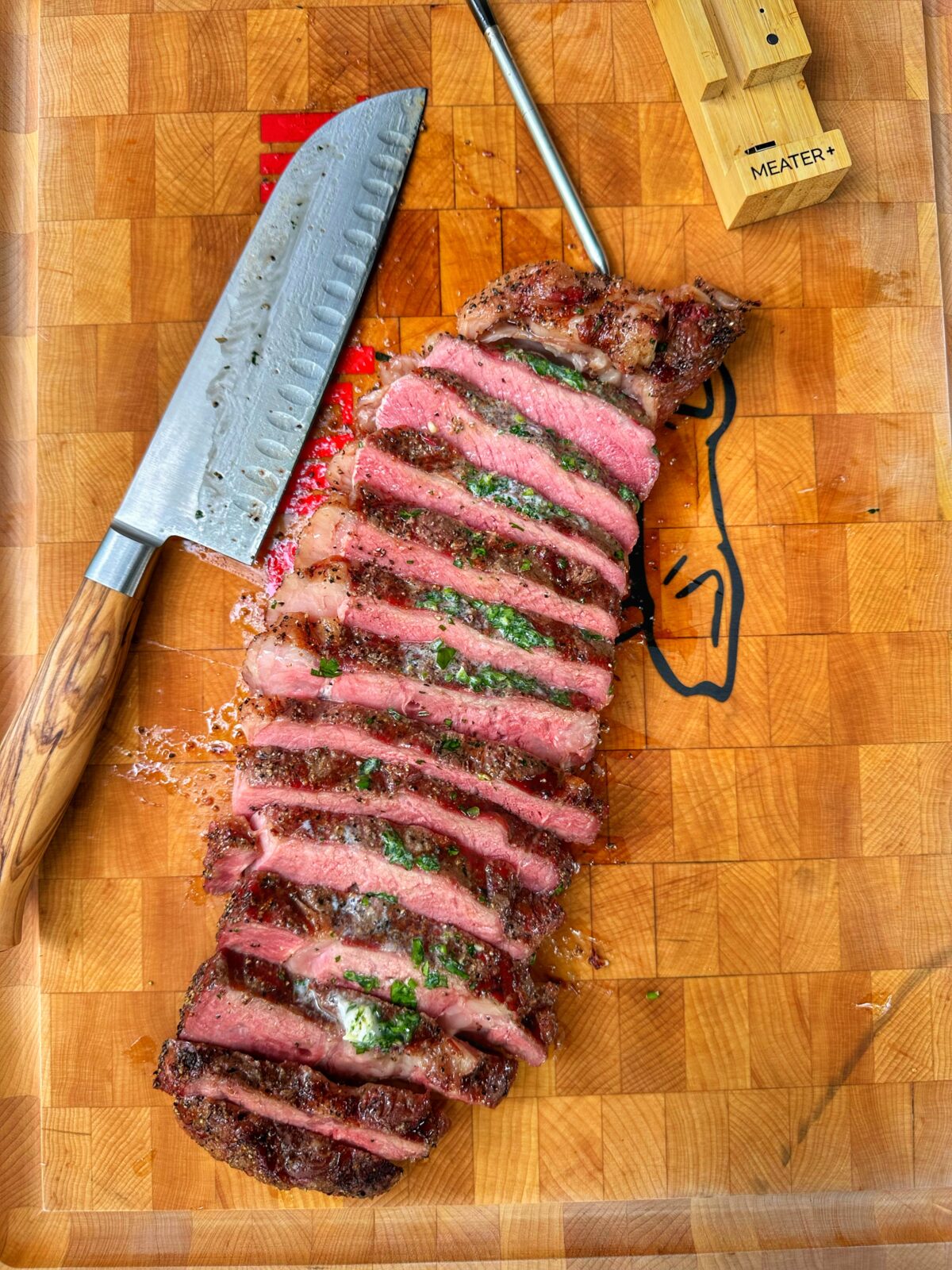 Sliced ribeye steak and a knife on a cutting board.