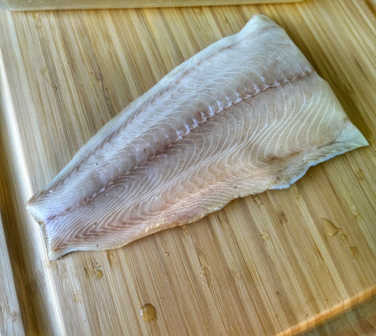 A filet of black cod on a cutting board.