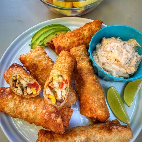 A plate of finished southwest egg rolls on a plate with garnish.