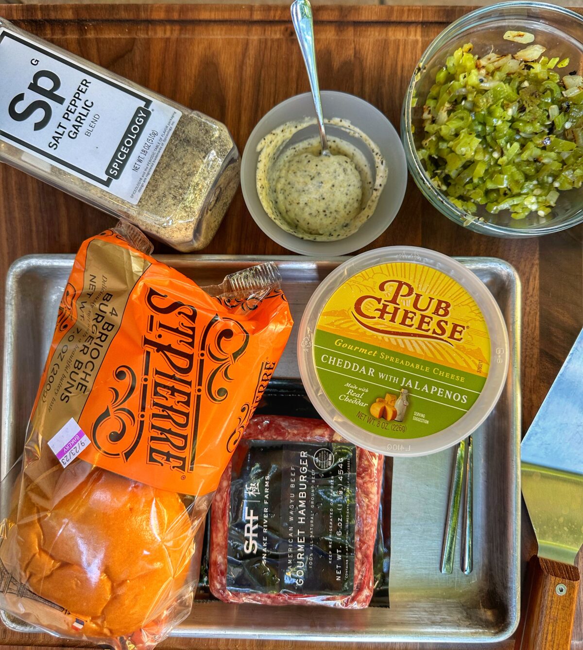 Green chile smash burger ingredients on a cutting board.