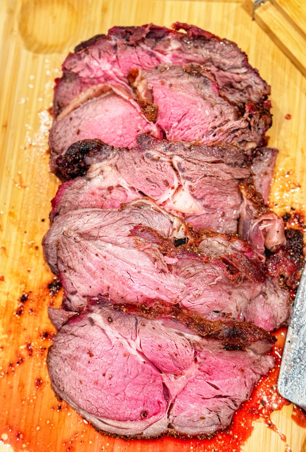 Sliced smoked-fried prime rib on a cutting board.