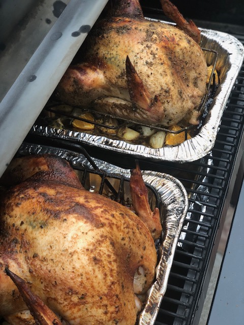 Two turkeys in pans in a Traeger grill.