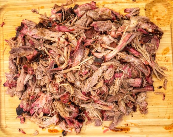 A pile of pulled pork on a cutting board.