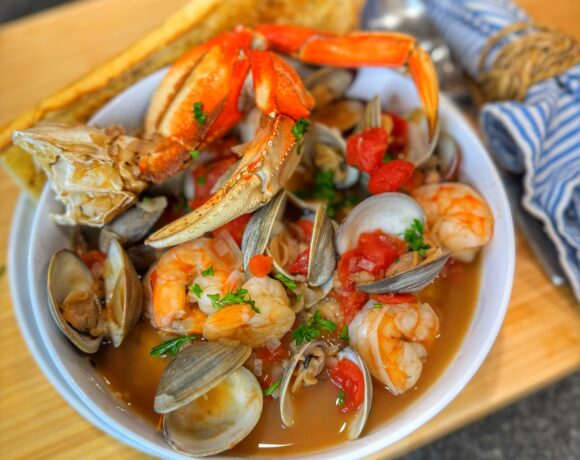 A bowl of cioppino on a cutting board.