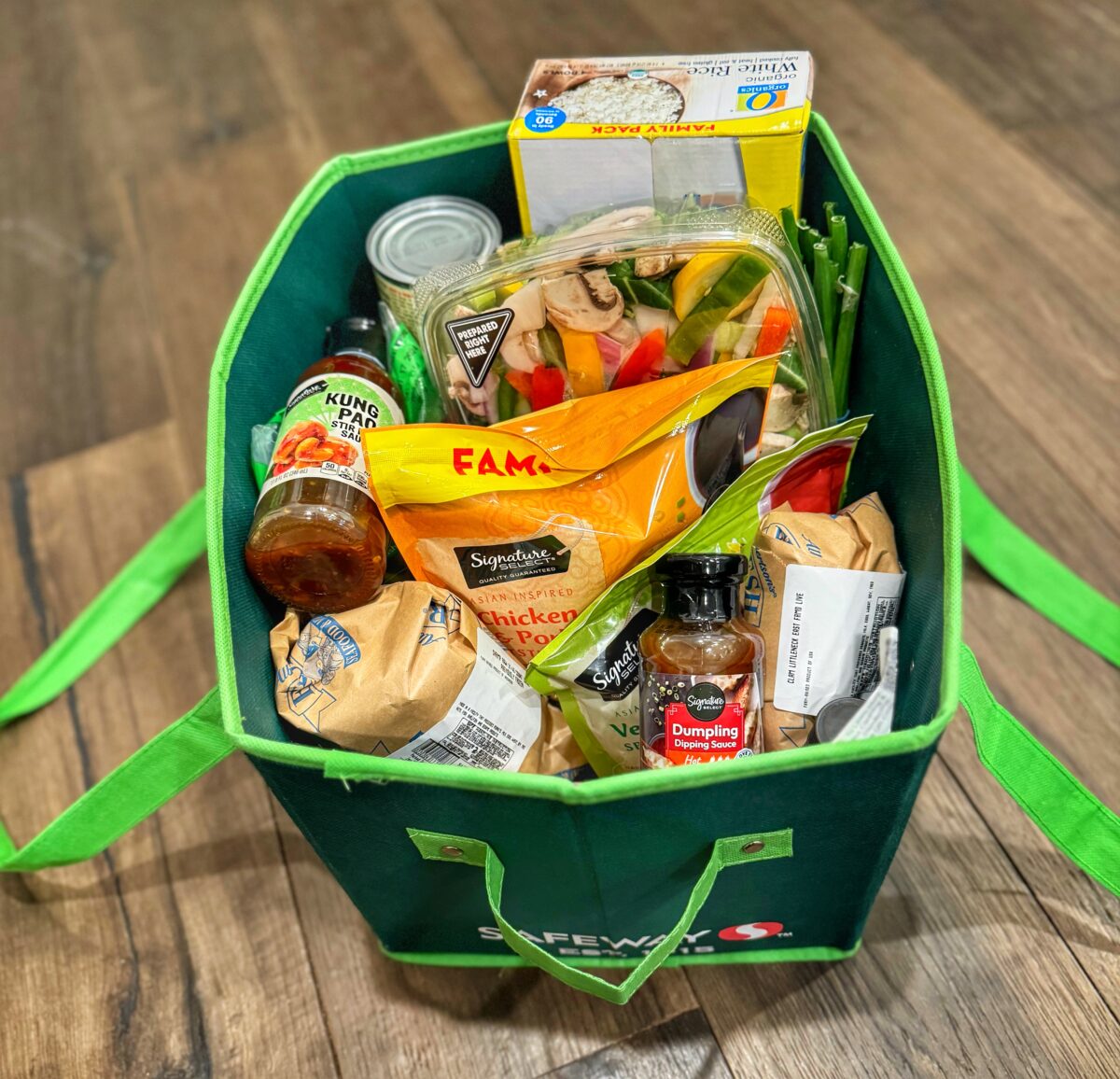 A green grocery tote full of groceries from Safeway.