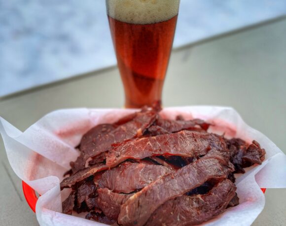 A basket of Traeger smoked teriyaki beef jerky with a glass of beer.