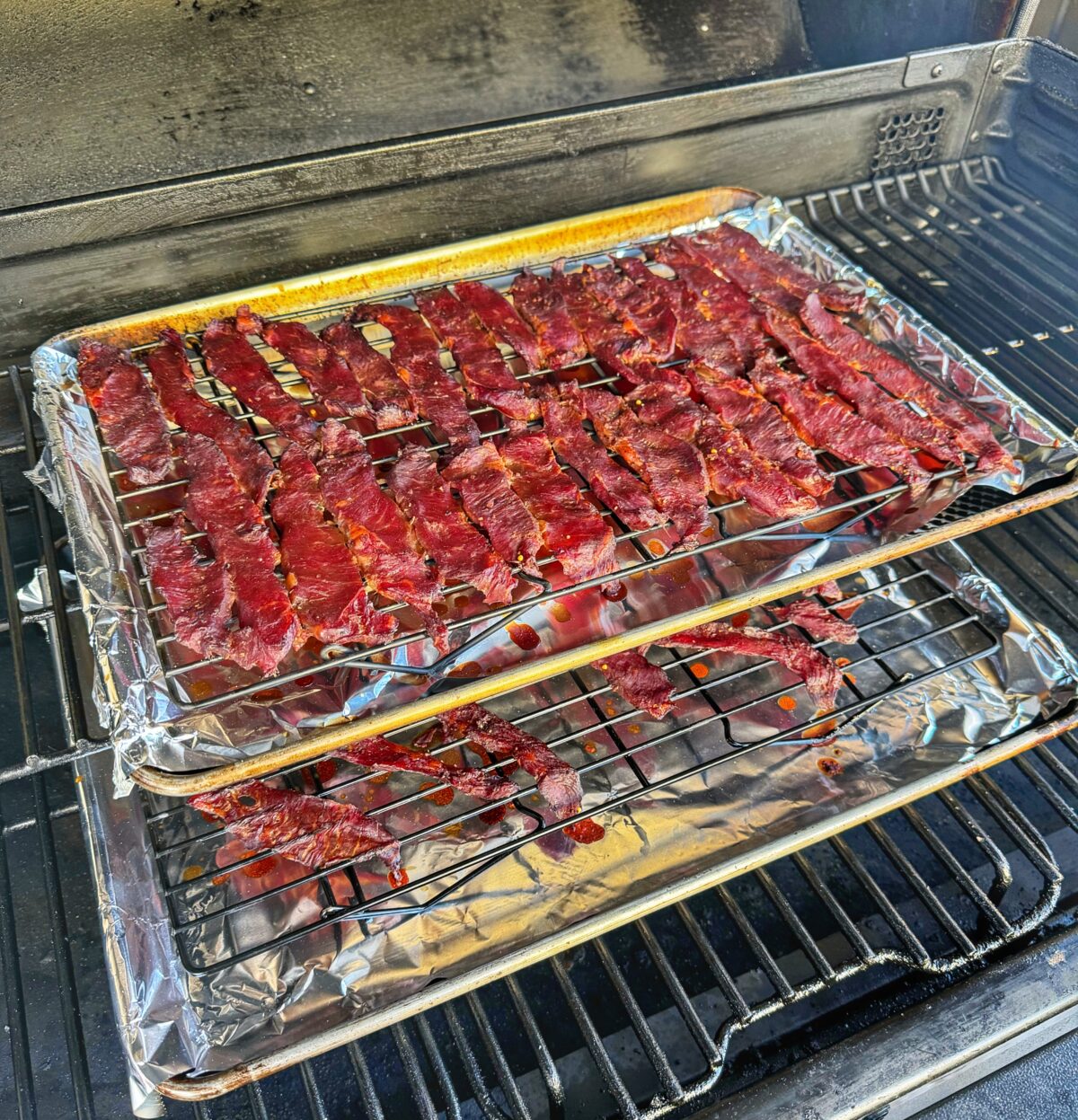 Two trays of teriyaki beef jerky smoking on the Traeger.