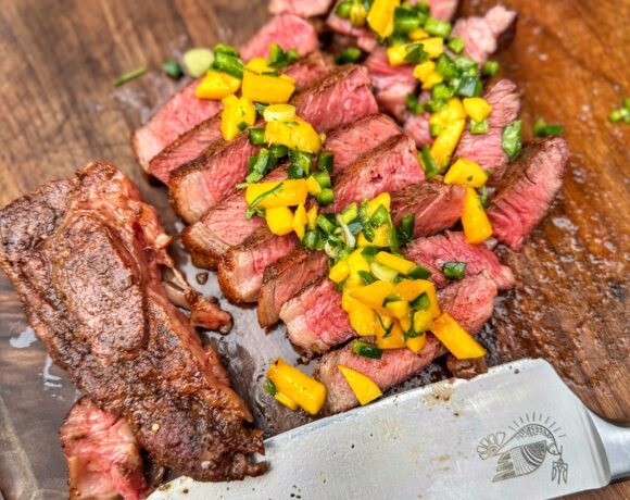 Overhead shot of the final smoked ribeye with mango poblano salsa, sliced and served.