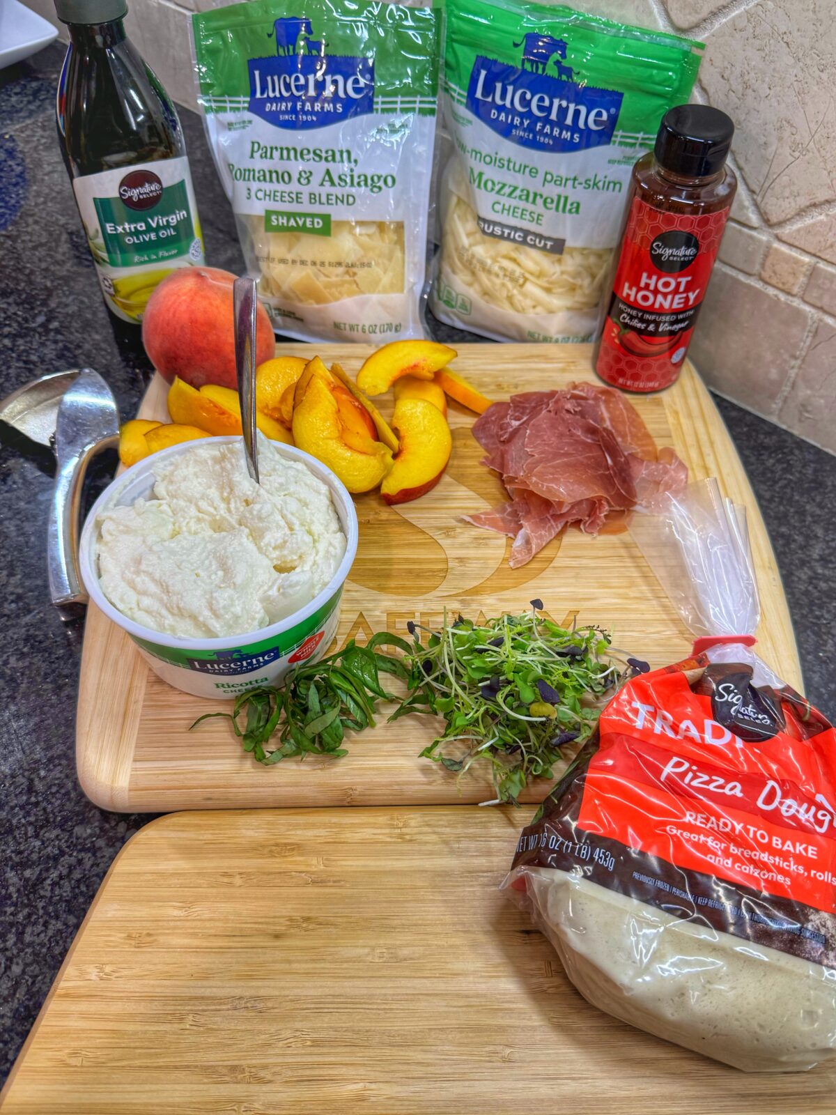 Fresh Safeway ingredients for pizza including ricotta, mozzarella, parmesan, prosciutto, peaches, arugula, olive oil, and hot honey.
