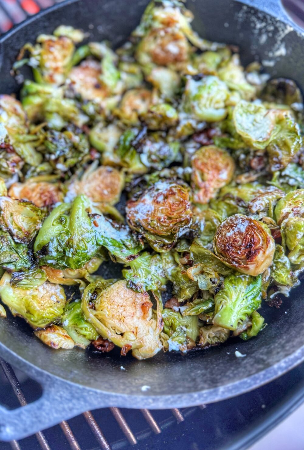 Crispy wood fired Brussels sprouts with bacon and goat cheese in cast iron skillet.