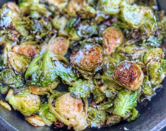 Crispy wood fired Brussels sprouts with bacon and goat cheese in cast iron skillet.