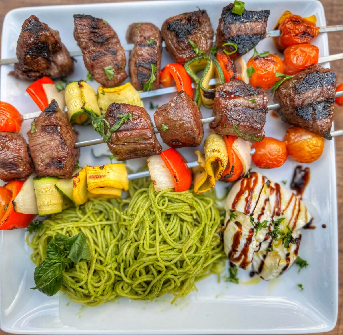 Close-up of finished grilled skewers with blistered vegetables and seared steak.