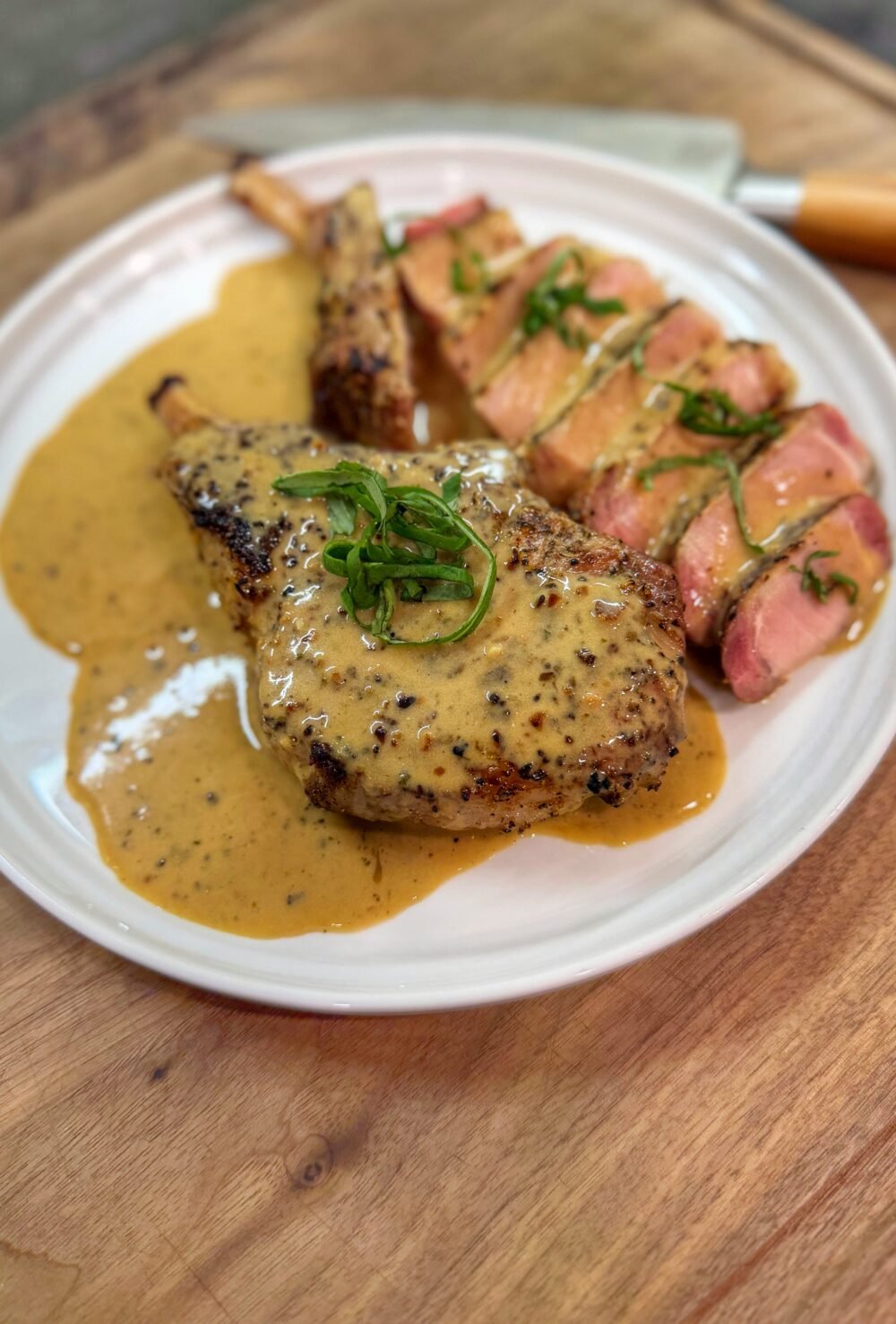 Garlic ranch pork chops on the Traeger served sliced with creamy ranch pan sauce and fresh basil garnish.