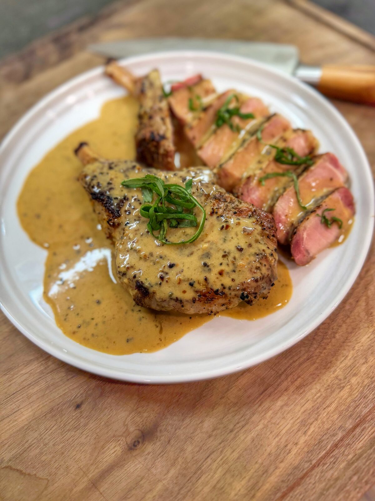 Garlic ranch pork chops on the Traeger served sliced with creamy ranch pan sauce and fresh basil garnish.
