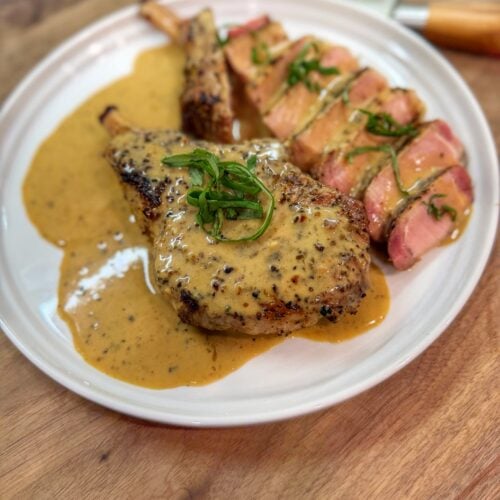 Garlic ranch pork chops on the Traeger served sliced with creamy ranch pan sauce and fresh basil garnish.