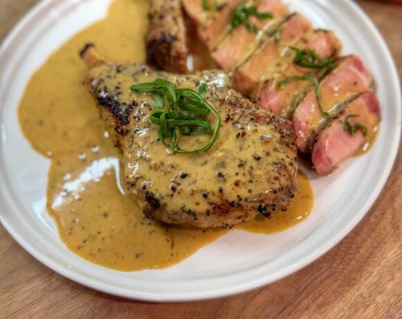 Garlic ranch pork chops on the Traeger served sliced with creamy ranch pan sauce and fresh basil garnish.