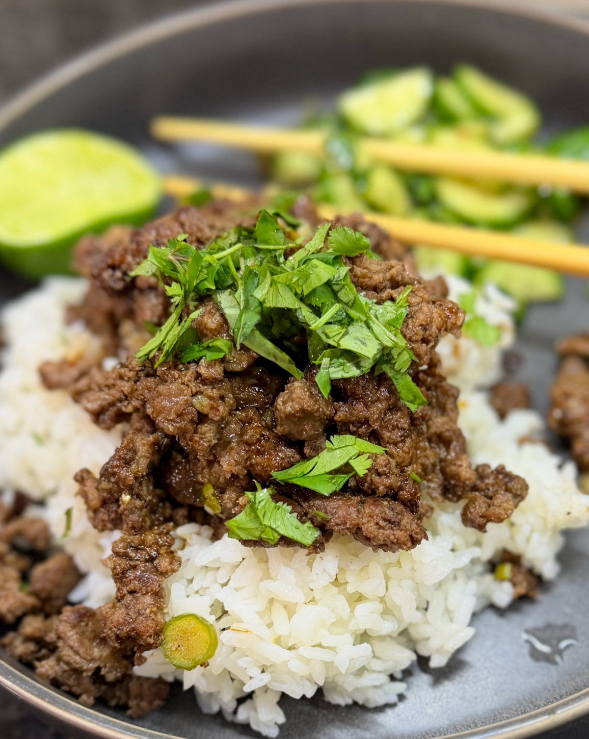 Quick griddled beef larb served over white rice and topped with fresh cilantro, with cucumber salad and lime on the side.