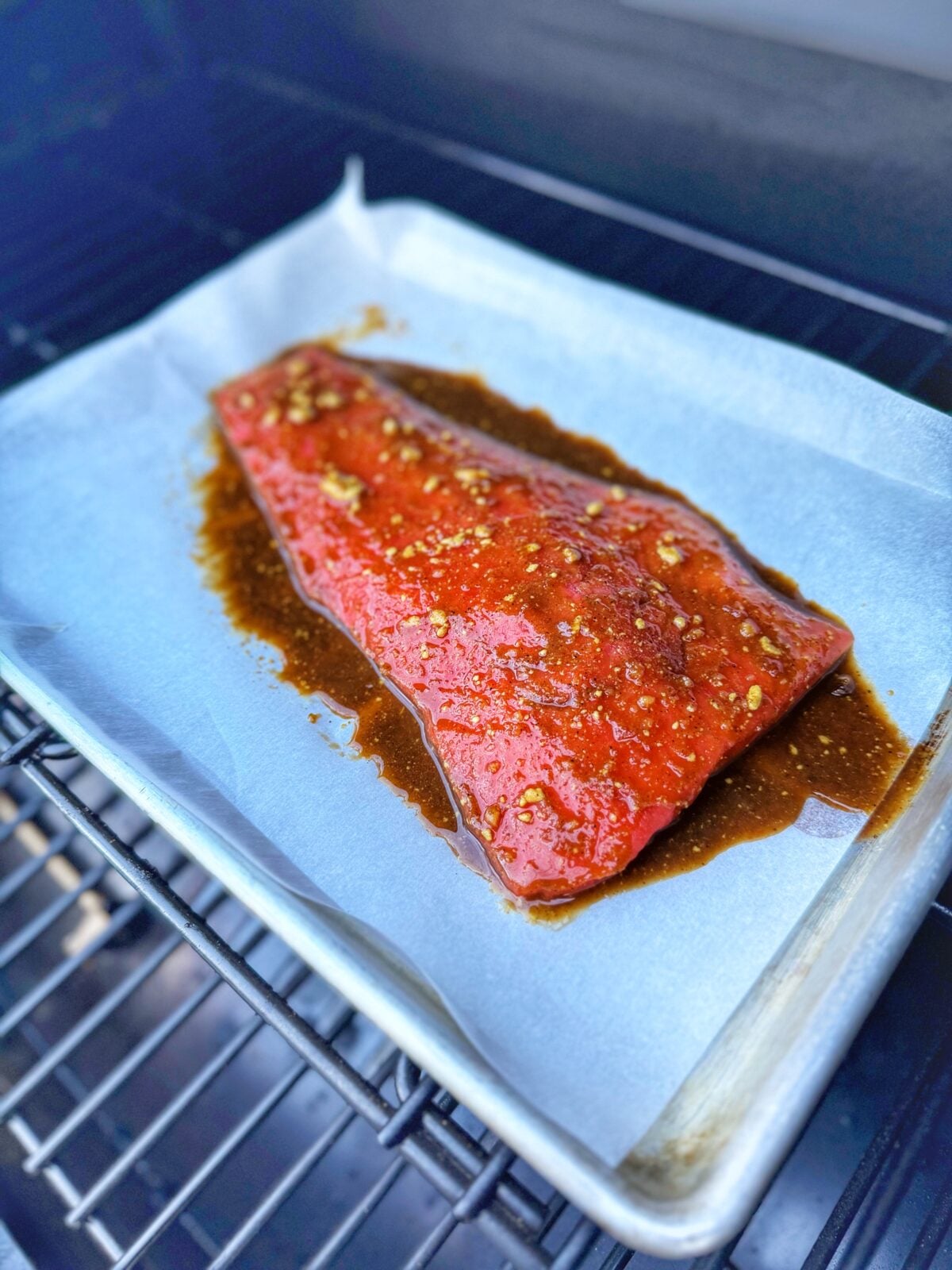 Salmon filet on parchment-lined cookie sheet cooking on the Pit Boss Navigator pellet grill.