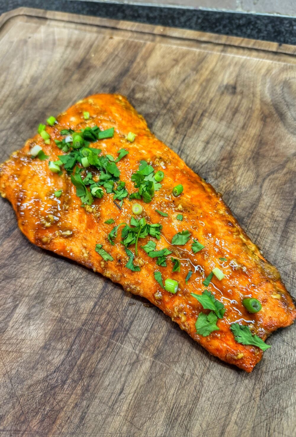 Cooked bourbon brown sugar salmon filet with caramelized glaze resting on a cutting board.