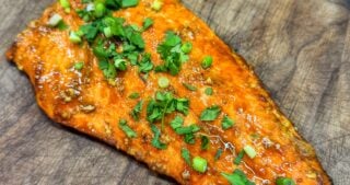 Cooked bourbon brown sugar salmon filet with caramelized glaze resting on a cutting board.