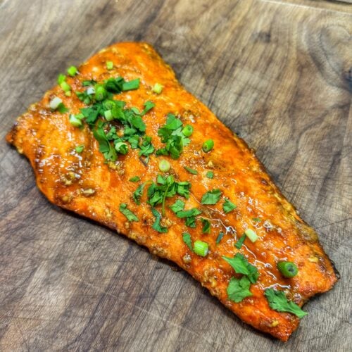 Cooked bourbon brown sugar salmon filet with caramelized glaze resting on a cutting board.