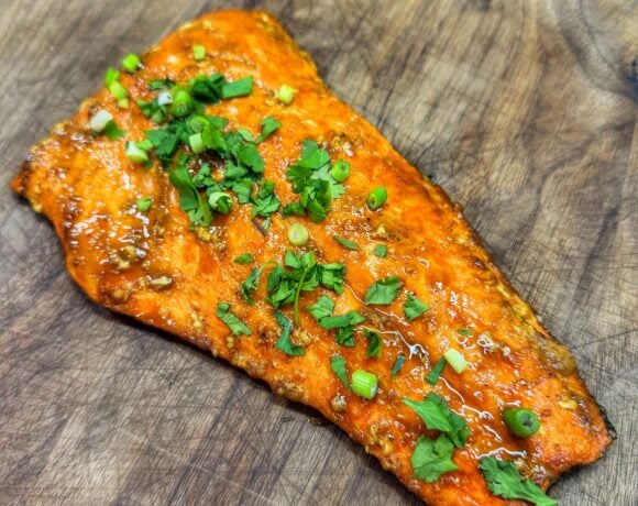 Cooked bourbon brown sugar salmon filet with caramelized glaze resting on a cutting board.