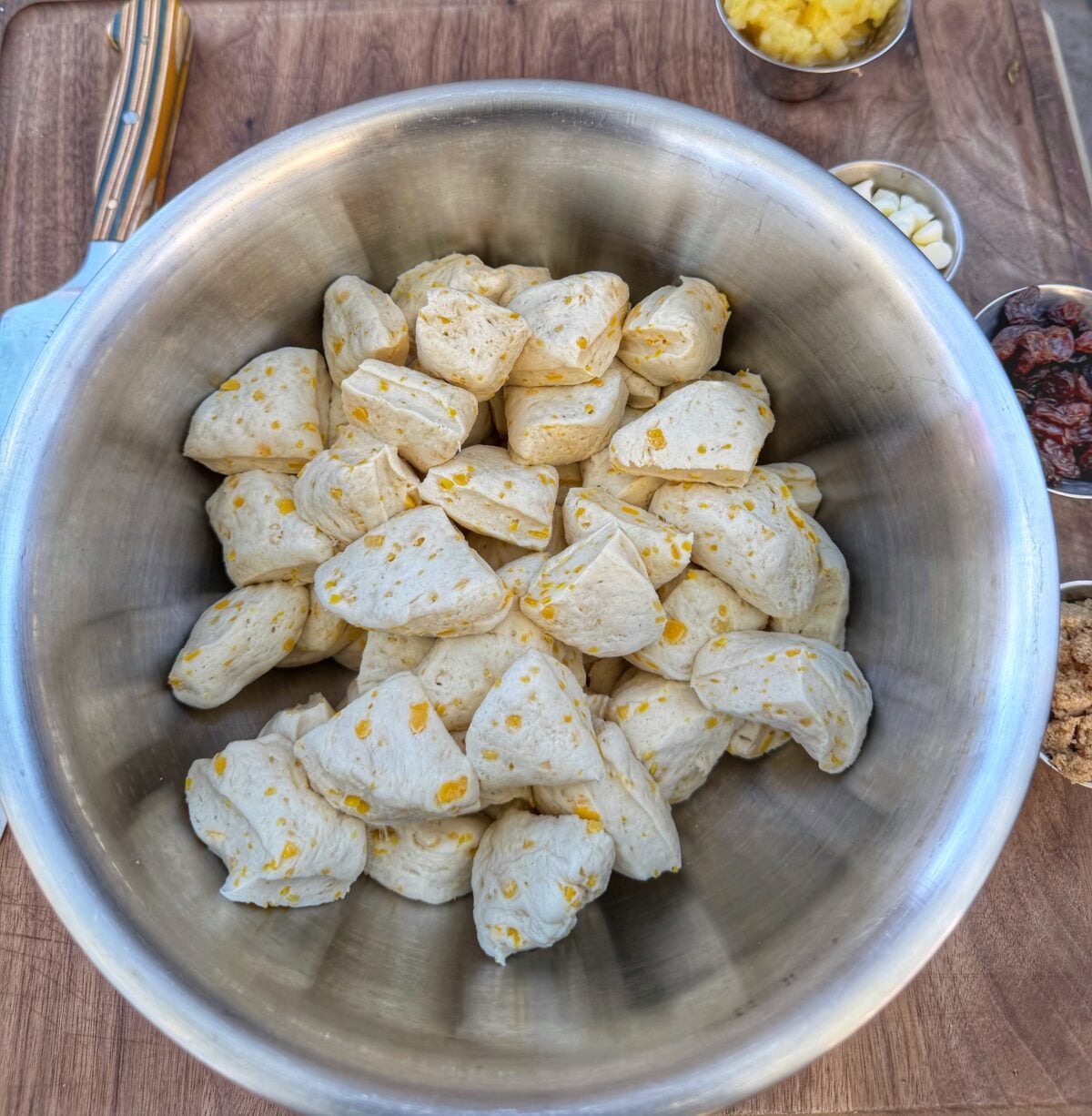 Quartered biscuit dough pieces in a large mixing bowl ready to be combined with carrot cake ingredients.