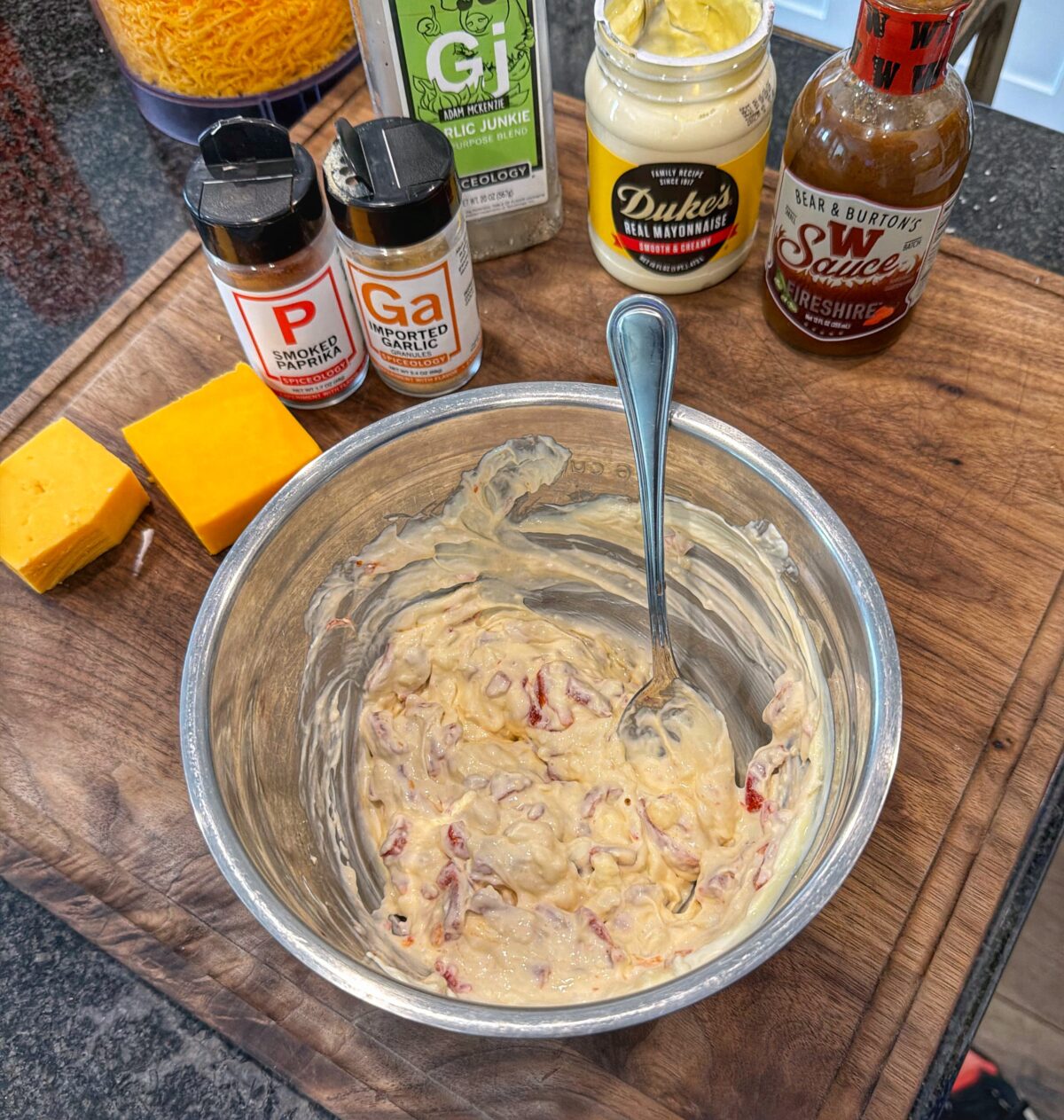 Creamy mixture of cream cheese, mayonnaise, and pimentos partially combined in a metal mixing bowl.
