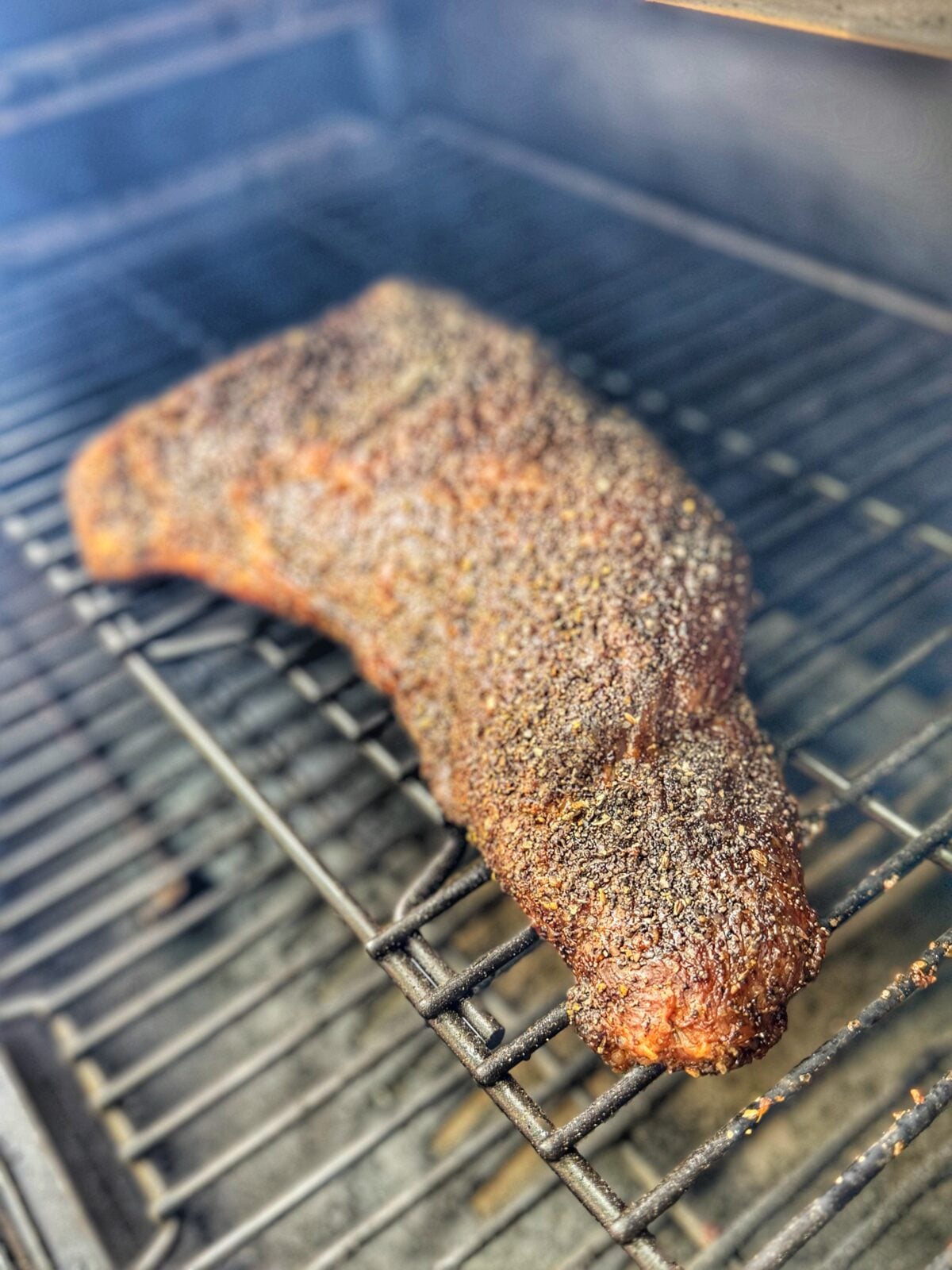 Tri tip roast cooking on grill grates.