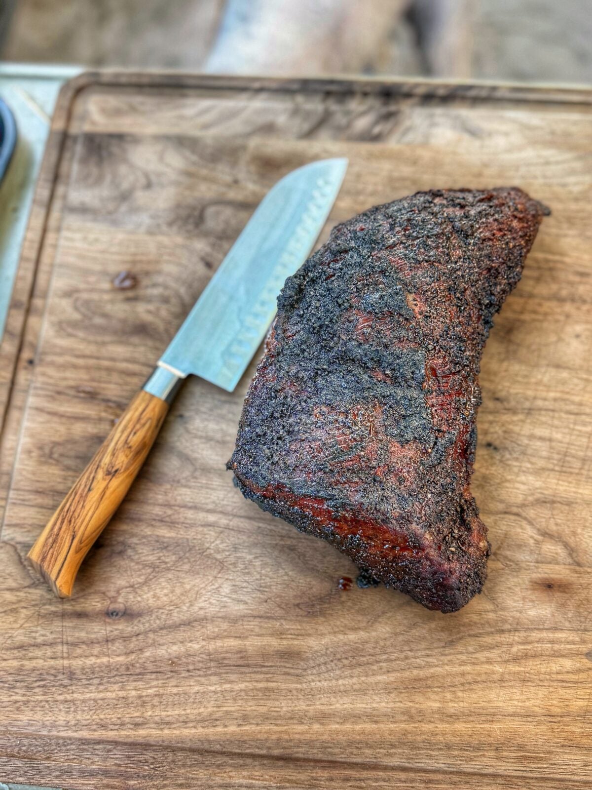 Cooked tri tip roast resting on a wooden cutting board.