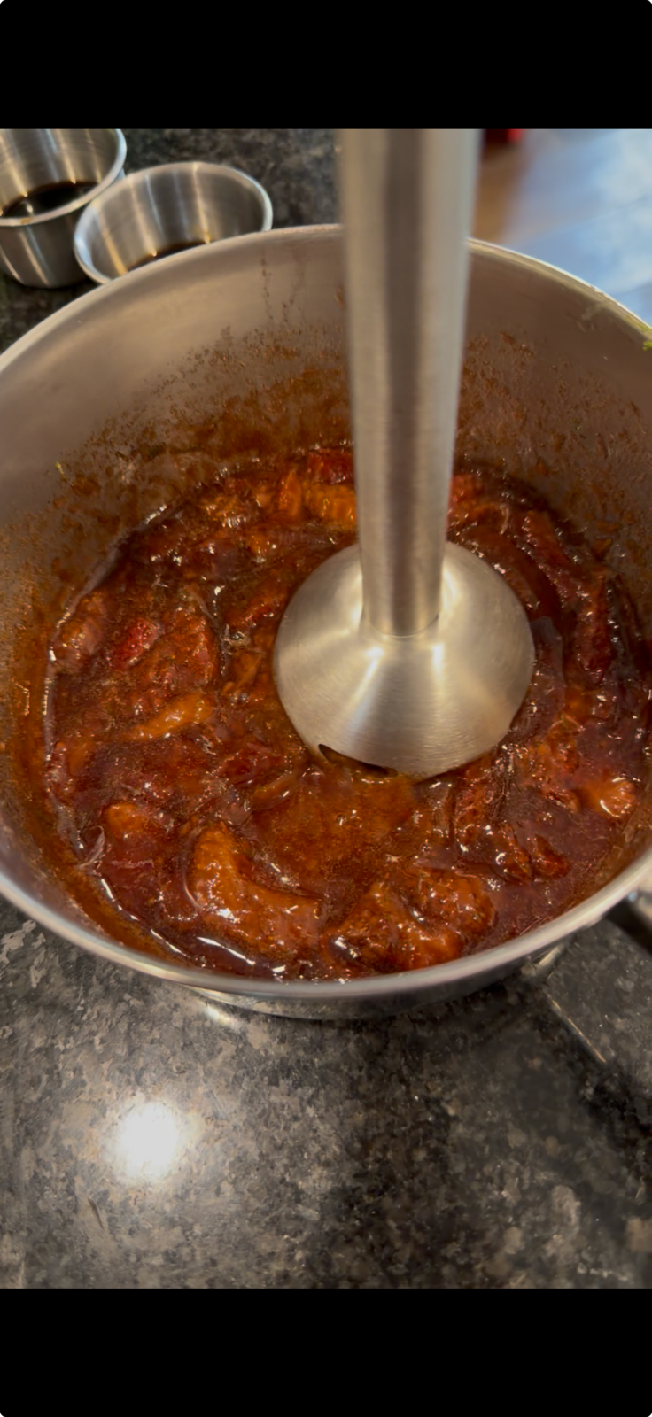 Strawberry glaze blending in a saucepan with an immersion blender.