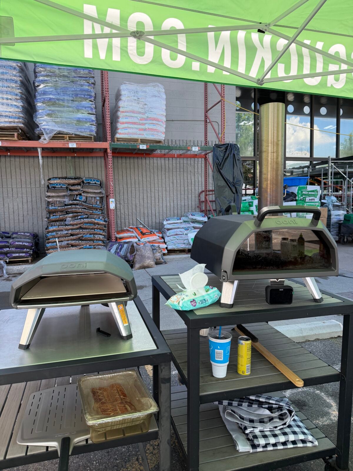 Two Ooni pizza ovens set up under a McGuckin Hardware tent at an outdoor event.