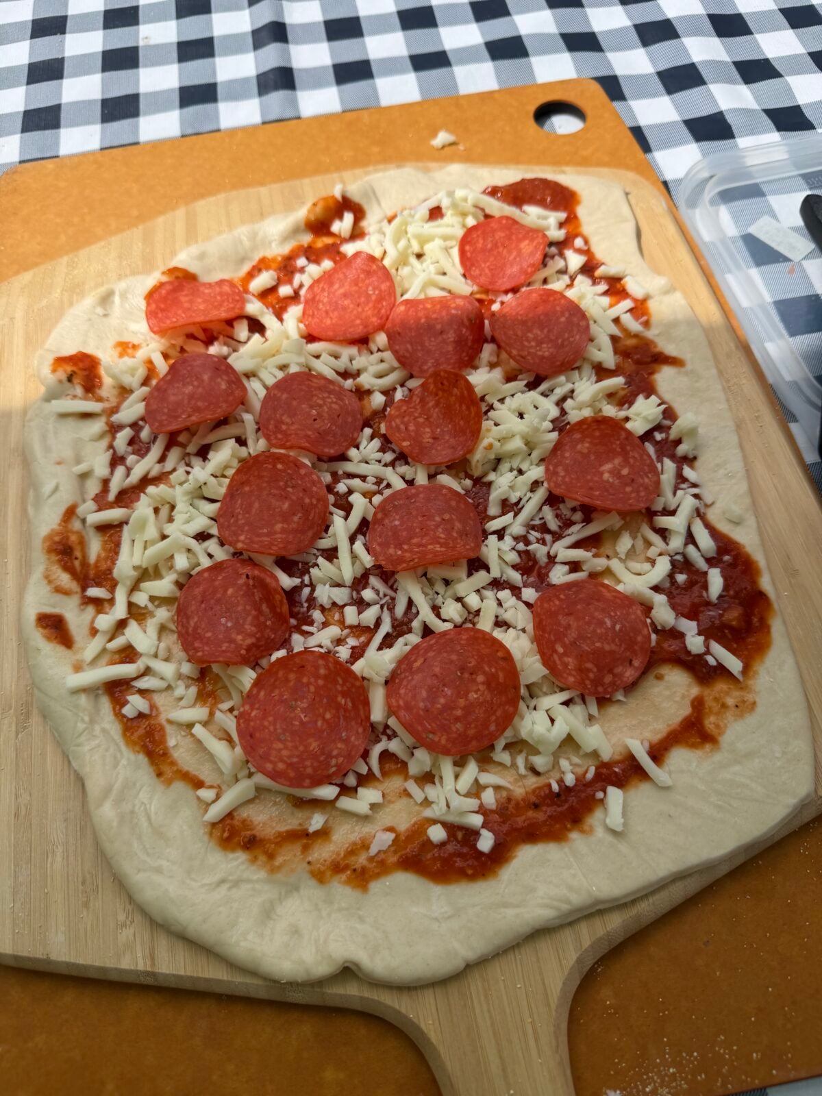 Prepared pizza dough topped with pizza sauce, shredded mozzarella cheese, and pepperoni before baking.