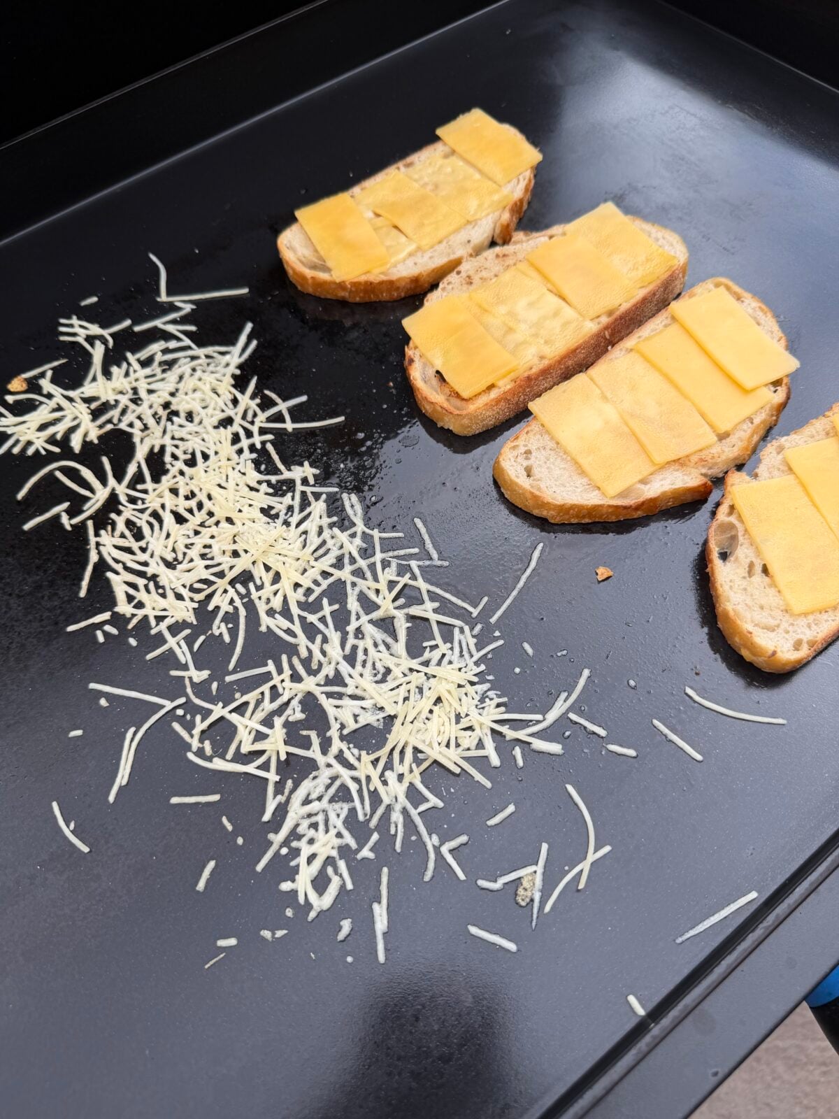 Cabot Creamery Gouda cheese melting on toasted sourdough bread while Parmesan crisps on a Pit Boss griddle.