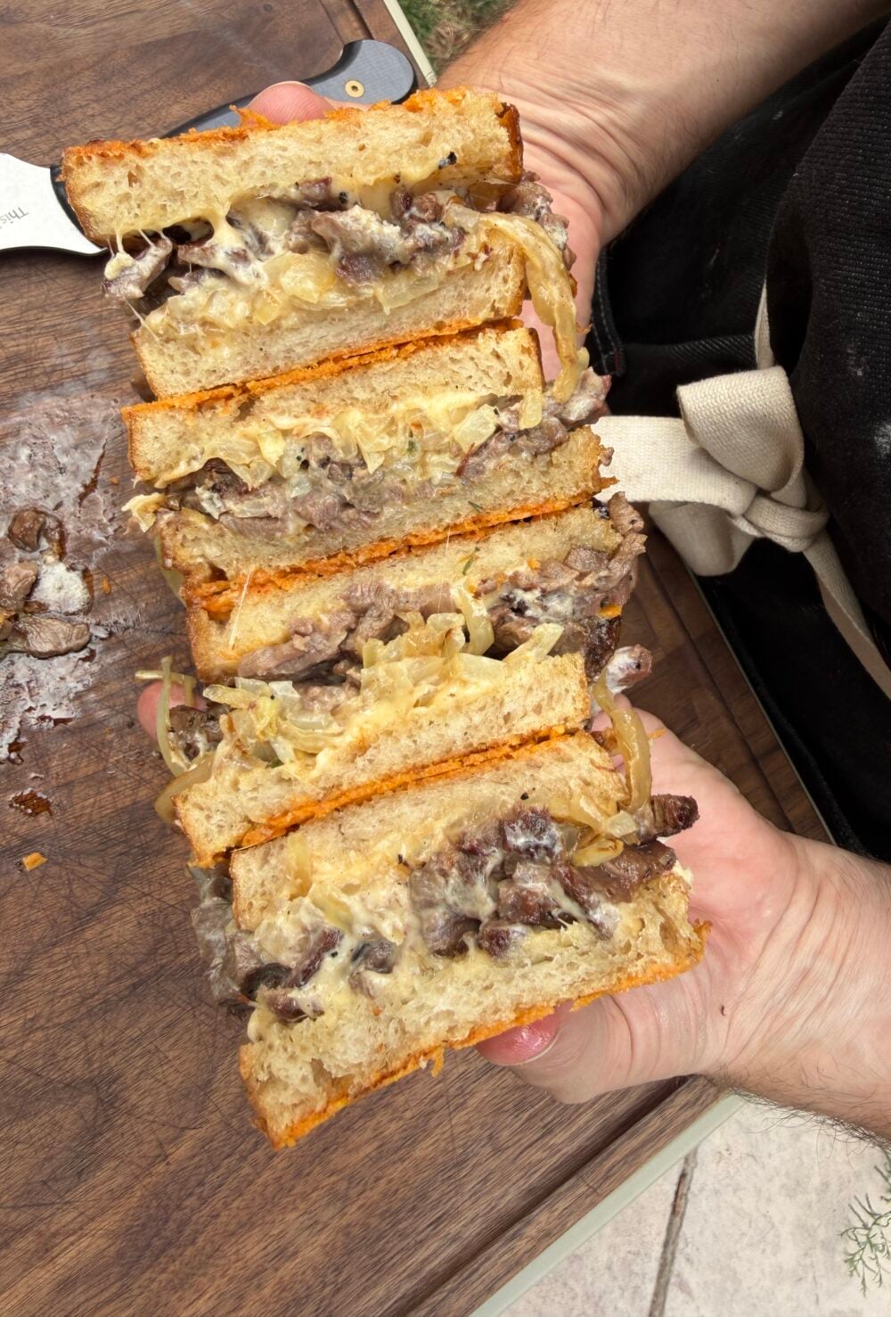 Close-up of a sliced French Onion Steak Melt made with leftover smoked ribeye cap, caramelized onions, melted Cabot Gouda cheese, horseradish mayo, and Parmesan-crusted sourdough on a Pit Boss Griddle.