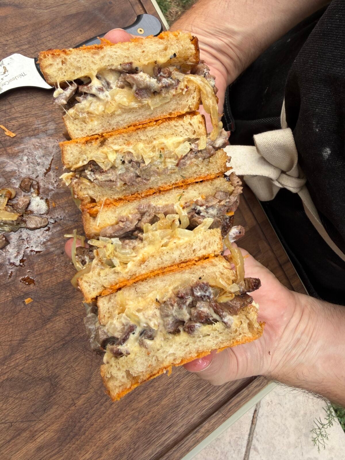 Close-up of a sliced French Onion Steak Melt made with leftover smoked ribeye cap, caramelized onions, melted Cabot Gouda cheese, horseradish mayo, and Parmesan-crusted sourdough on a Pit Boss Griddle.