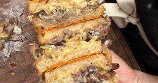 Close-up of a sliced French Onion Steak Melt made with leftover smoked ribeye cap, caramelized onions, melted Cabot Gouda cheese, horseradish mayo, and Parmesan-crusted sourdough on a Pit Boss Griddle.