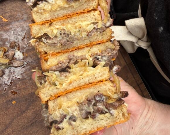 Close-up of a sliced French Onion Steak Melt made with leftover smoked ribeye cap, caramelized onions, melted Cabot Gouda cheese, horseradish mayo, and Parmesan-crusted sourdough on a Pit Boss Griddle.