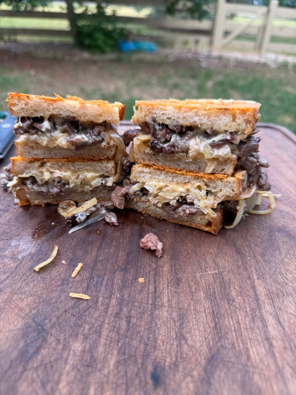 Close-up cross section of a French Onion Steak Melt showing smoked ribeye cap, melted Gouda cheese, caramelized onions and crispy Parmesan crust.